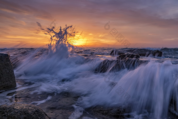 令人惊异的飞溅海水日出的海岸的黑色的海美丽的运动模糊海波在的岩石低角视图