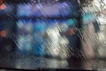 雨滴的窗口水滴玻璃的表面湿玻璃城市灯散景在的雨