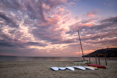 一些冲浪板的海滩海滨日落时间与美丽的云水体育运动背景