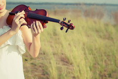 美丽的女人站玩的小提琴的草地