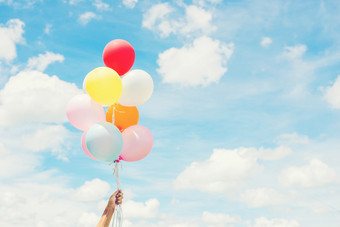 女人生活方式概念女人手持有群彩色的气球与蓝色的天空女人生活方式概念女人手持有群彩色的
