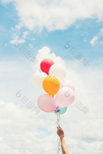 女人生活方式概念女人手持有群彩色的气球与蓝色的天空女人生活方式概念女人手持有群彩色的
