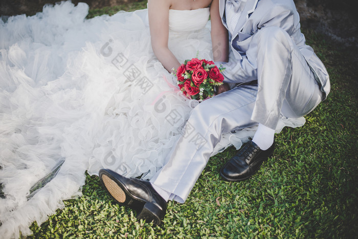 新娘持有婚礼红色的玫瑰花束手的新郎拥抱新娘持有婚礼红色的玫瑰花束手的新郎拥抱他的新娘在一起婚礼情人概念
