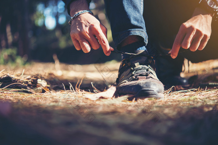 年轻的徒步旅行者男人。关系的鞋带他的鞋在假期回来年轻的徒步旅行者男人。关系的鞋带他的鞋在假期徒步旅行森林