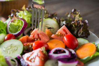 关闭新鲜的蔬菜沙拉的碗与乡村老木背景健康的食物概念关闭新鲜的蔬菜沙拉的碗与乡村老