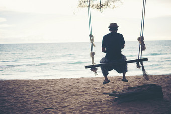 年轻的男人。看日落独自一人坐着波动的海滩年轻的男人。看日落独自一人坐着波动的海滩日落