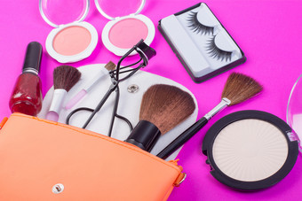 前视图使袋与化妆品美产品溢出出到粉红色的背景前视图使袋与化妆品美产品溢出