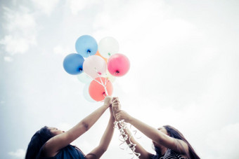 快乐集团女孩朋友手持有五彩缤纷的气球