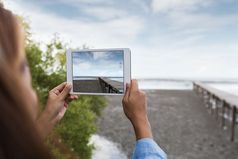 女人使用数字平板电脑采取景观照片