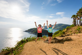 两个<strong>女孩</strong>妈妈。和女儿跳与快乐的山全景海洋和岛的观点角phromthep普吉岛泰国