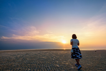 年轻的女<strong>人</strong>旅游<strong>漫步</strong>的海滩看的美丽的自然景观色彩斑斓的的天空和的海在日落纳通日落的观点寒这封信他尼府泰国女<strong>人漫步</strong>的海滩日落