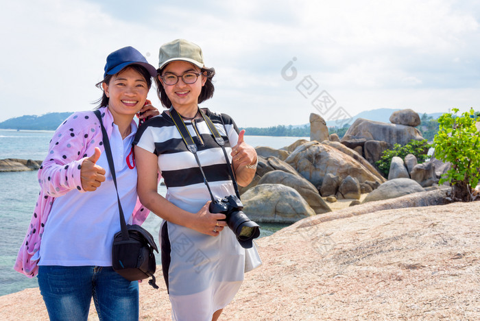 妈妈。和女儿站拇指和微笑幸福的欣欣Yai和美丽的自然景观蓝色的海和天空在夏天旅行KOH寒岛这封信他尼府泰国妈妈。和女儿欣欣Yai的观点