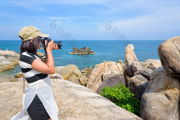 年轻的女人是使用数码单反相机相机摄影的欣欣Yai和美丽的自然景观蓝色的海和天空在夏天旅行KOH寒岛这封信他尼府泰兰女人采取照片的欣欣Yai