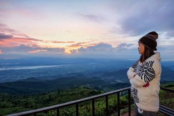 女人旅游毛衣衣服站看的美丽的自然景观的森林和山在的日出的高峰的早....府塔普书的观点碧差汶泰国女人旅游看的日出