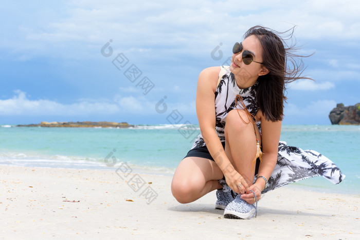 美丽的女人旅游穿sunglasse蹲绑定绳子运动鞋的海滩附近的海在的漫步塔鲁陶岛的夏天假期satun泰国女人绑定绳子运动鞋的海滩泰国