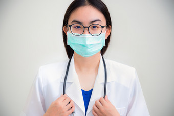 工作室肖像前面脸美丽的亚洲年轻的女人医生与听诊器白色统一的穿眼镜和绿色面具保护电晕病毒为健康看相机灰色的背景女人医生与听诊器白色统一的