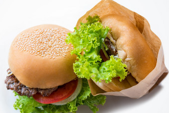 特写镜头前视图两个汉堡使从猪肉牛肉绿色生菜面包洋葱白色芝麻和番茄纸袋白色表格背景使首页汉堡美味的美国快食物前视图两个汉堡白色表格