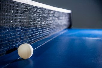 特写镜头一个白色球的蓝色的平发出难闻的气味表格与黑色的网表格网球桨体育竞争设备室内活动和锻炼为概念背景特写镜头白色表格网球球和黑色的网
