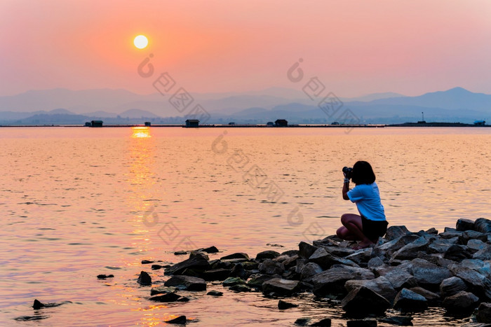 年轻的女人海滨取照片数码单反相机相机美丽的自然景观太阳的明亮的橙色天空在的山和湖水日落背景krasiao大坝suphan武里府泰国年轻的女人海滨取照片日落