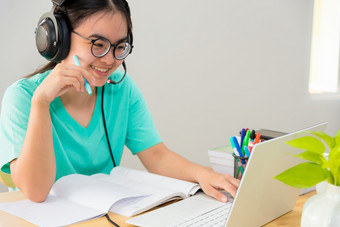 亚洲年轻的女人学生与眼镜耳机十几岁的女孩研究快乐坐着看<strong>视频</strong>会议移动PC电脑大学类在线互联网学习距离<strong>教育</strong>从首页亚洲女人学生类在线互联网学习