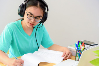 亚洲女人学生十几岁的女孩与眼镜耳机坐着快乐微笑<strong>看</strong>写作笔记书移动PC电脑表格<strong>学习</strong>在线研究教育从的类大学首页亚洲女人写作笔记书<strong>学习</strong>在线