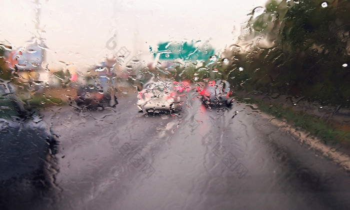 开车车的雨和风暴重交通视图通过挡风玻璃与雨滴在开车车浅深度场