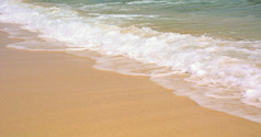 特写镜头黄金沙子海滩与绿松石海洋水与波