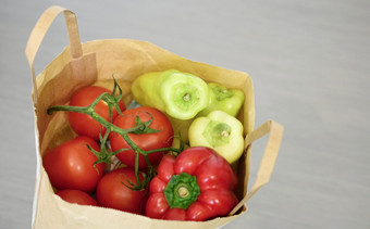 前视图杂货店纸袋完整的西红柿和绿色辣椒灰色背景完整的纸袋与蔬菜