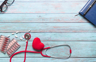 医疗保健和医疗概念红色的听诊器和医学的蓝色的木背景