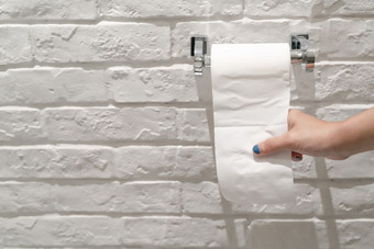 女手拉白色组织纸从组织卷的厕所