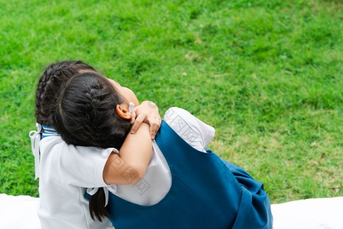 两个小亚洲女孩姐妹拥抱快乐帖子学校统一的回来学校概念