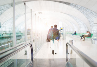 旅行者与旅行袋行李走的机场终端人行道为空气旅行模糊运动