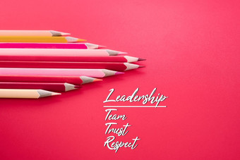 领导业务概念红色的颜色铅笔引领其他颜色与词领导团队信任和尊重粉红色的背景