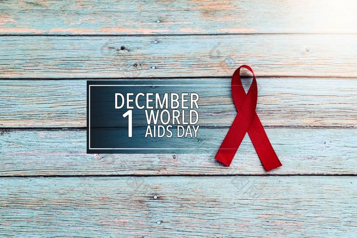 世界健康一天艾滋病意识标志红色的丝带的战斗对艾滋病标志的蓝色的木背景