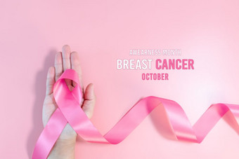 粉红色的丝带象征乳房<strong>癌症</strong>意识月运动女人手持有的粉红色的丝带粉红色的背景