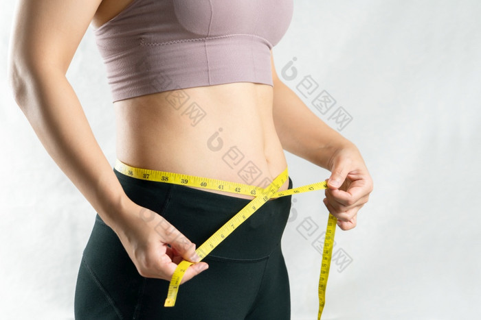 年轻的女人测量她的肚子腰与测量磁带女人饮食生活方式概念