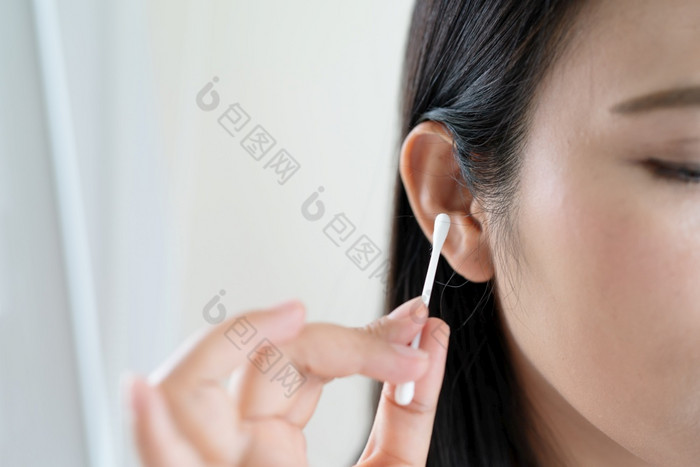 女人清洁耳朵与棉花拭子医疗保健和耳朵清洁概念