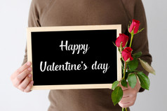 情人节rsquo一天概念男人。手持有红色的玫瑰和快乐情人节rsquo一天黑板站在白色背景