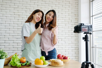 两个年轻的亚洲女人食物博客会说话的和拇指而<strong>记录视频视频</strong>博客概念人食物和技术沟通