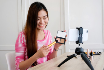 年轻的亚洲女人美博主显示如何使视频教程而记录智能手机