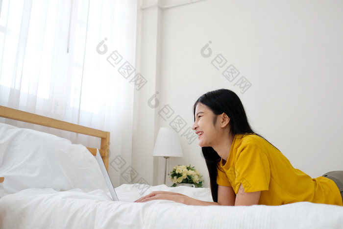 年轻的亚洲女人使用移动PC电脑床上她的床上房间背景与复制空间工作首页人和技术生活方式教育业务概念