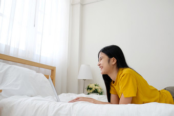 年轻的亚洲女人使用移动PC电脑床上她的床上房间背景与复制空间工作首页人和技术生活方式教育业务概念