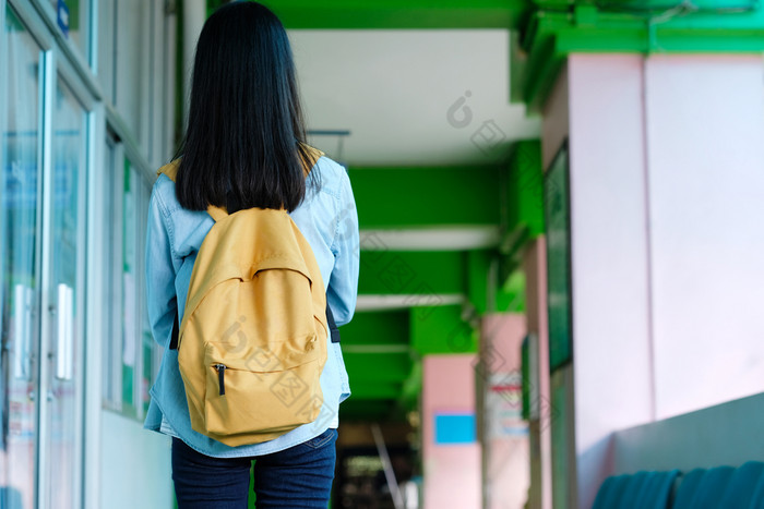 回来学生女孩持有书和携带学校袋而走学校校园背景教育回来学校概念