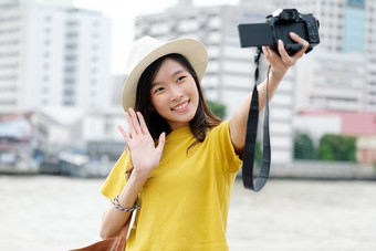 年轻的亚洲女旅行者采取自拍照片城市在户外背景旅行博主视频博客概念