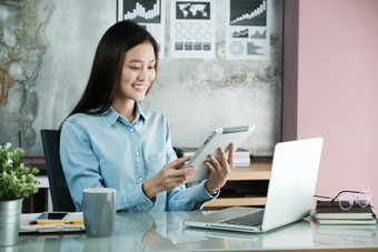 年轻的亚洲女商人使用平板电脑与微笑脸积极的情感<strong>办公室休闲办公室</strong>生活概念
