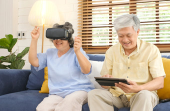 <strong>高级</strong>亚洲夫妇玩虚拟现实耳机和使用数字平板电脑首页生活房间与幸福情<strong>感</strong>退休生活方式和技术