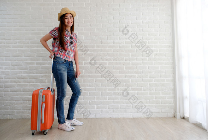 年轻的亚洲女人旅行者持有聪明的电话和行李白色房间与复制空间人夏天假期假期背景概念