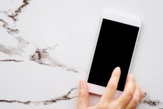 手使用白色聪明的电话与空白屏幕白色大理石表格背景为模拟模板技术和生活方式概念