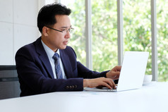 亚洲商人工作与移动PC电脑办公室业务概念