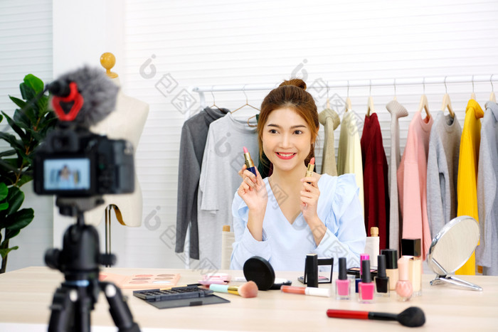 年轻的亚洲女人美视频博主显示口红为使美时尚视频博客概念人和技术沟通
